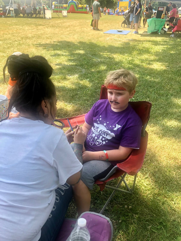 Child getting face painted by our Multi-system Youth Program Coordinator for Healthy Kids Day